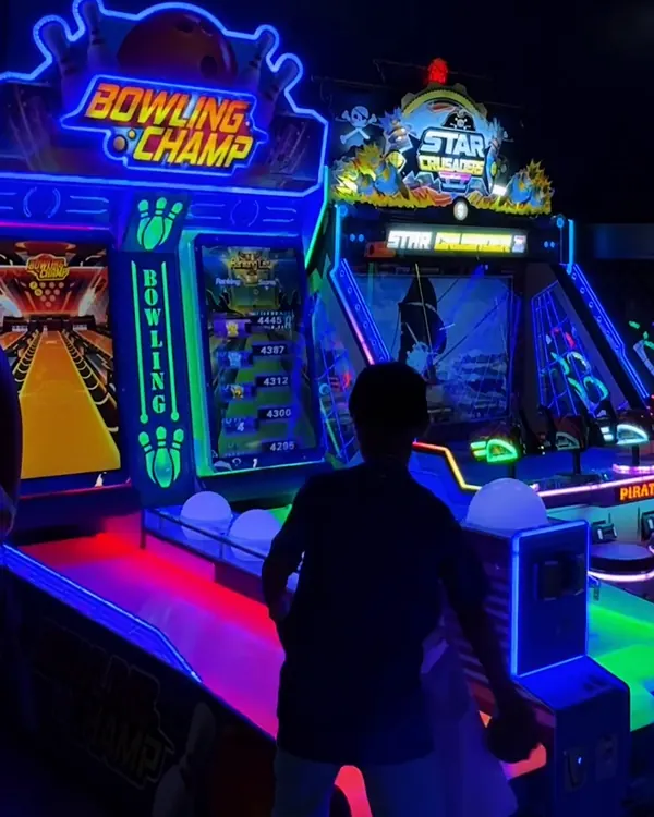Área de jogos com luz neon azul e máquinas de boliche